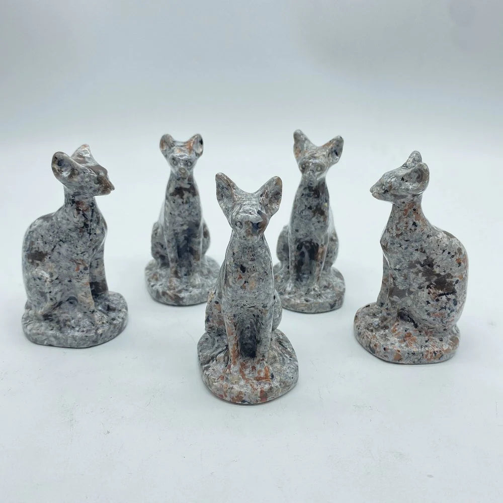A collection of five yooperlite carvings in the shape of stylized cats, each with a different color and size, set against a white background.