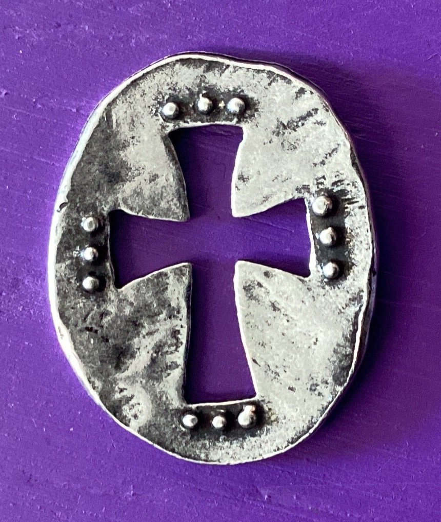 Silver horseshoe with a cross design on a purple background