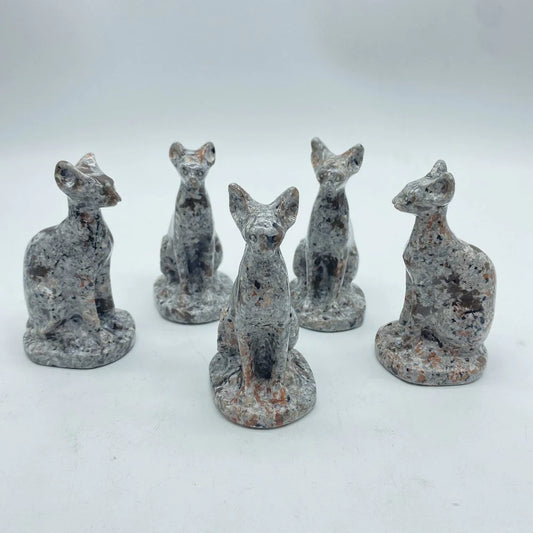 A collection of five yooperlite carvings in the shape of stylized cats, each with a different color and size, set against a white background.
